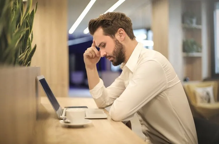 man-with-hand-on-temple-looking-at-laptop