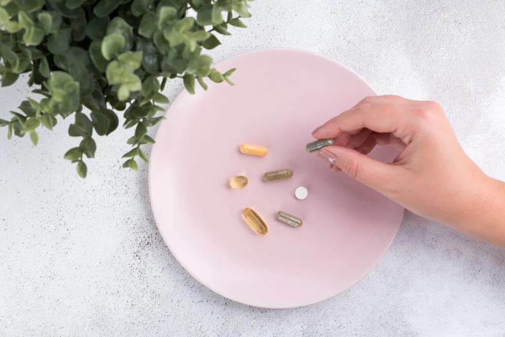 aerial-view-of-the-hand-of-a-young-woman-picking-up-a-supplement-capsule-amongst-other-pills