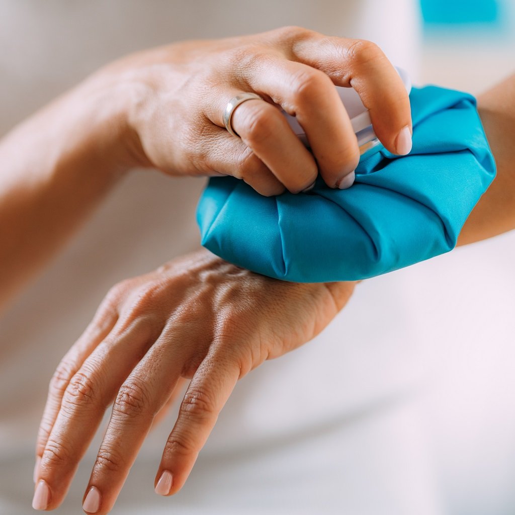 Wrist Pain Treatment. Woman Holding Ice Bag Compress on a Painful Wrist.